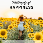 This image is used as a featured image for the article How to be Happy on My Philosophy Life. It shows a woman in a field of sunflowers with the sun on the horizon. She is wearing a hat and a blue short dress. The text in the image says Philosophy of happiness. How Aristotle can help you become happy.